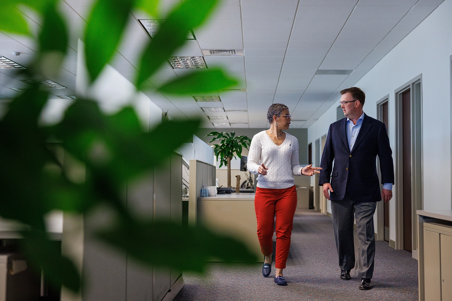 Two Summit employees have a conversation while walking down an office hallway.