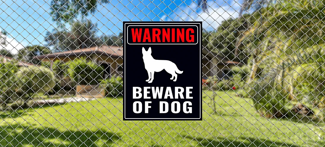 "Warning: Beware of Dog" sign on a chain link fence.